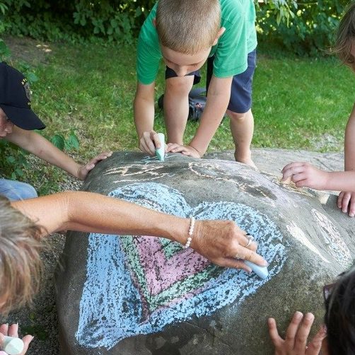 Kinder bemalen Fels mit einem Herzen